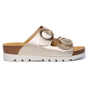 Gold Plakton Cora sandal with two wide metallic leather straps, round oversized buckles, cork and Memory Foam footbed, and a black lightweight sole.